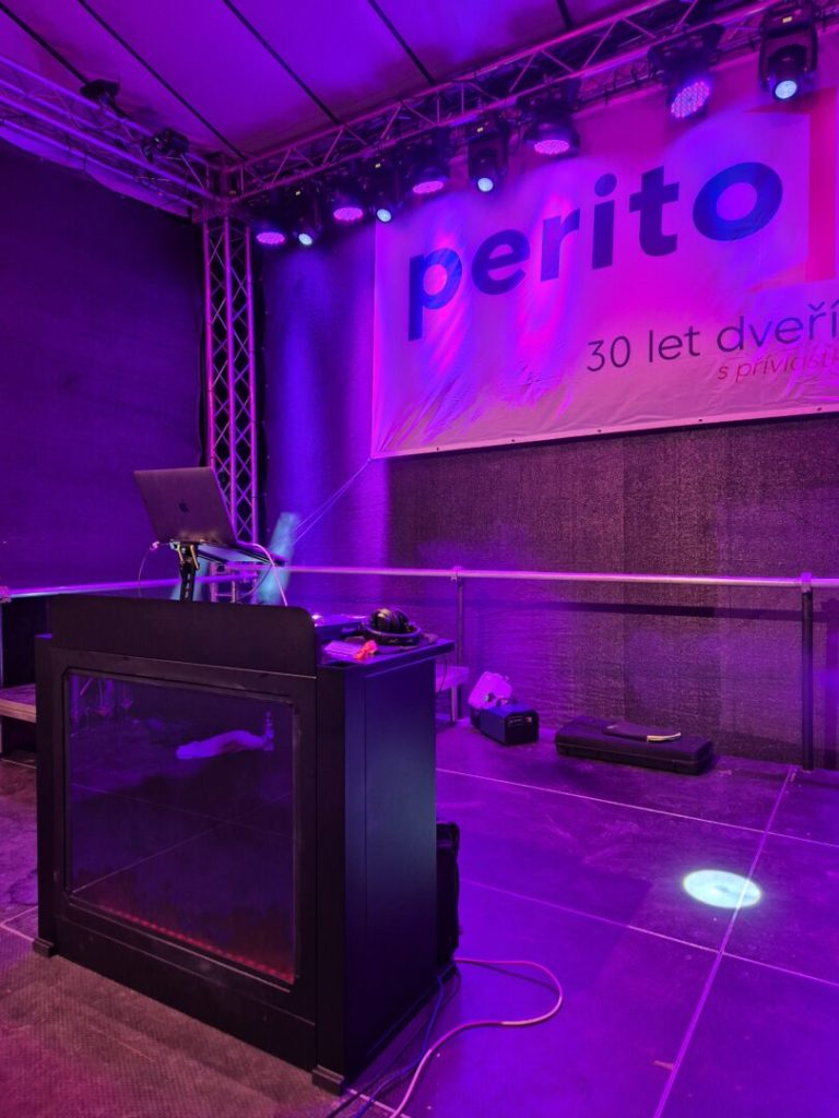 DJ pult a světelná rampa před bannerem k třicátému výročí firmy.