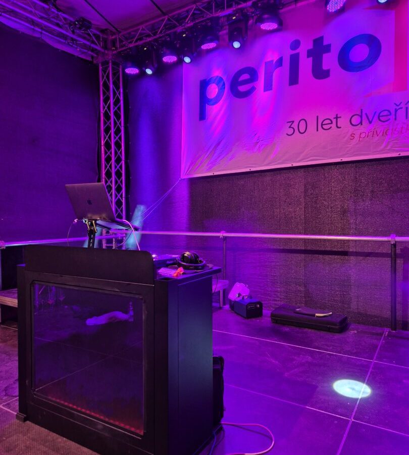 DJ pult a světelná rampa před bannerem k třicátému výročí firmy.